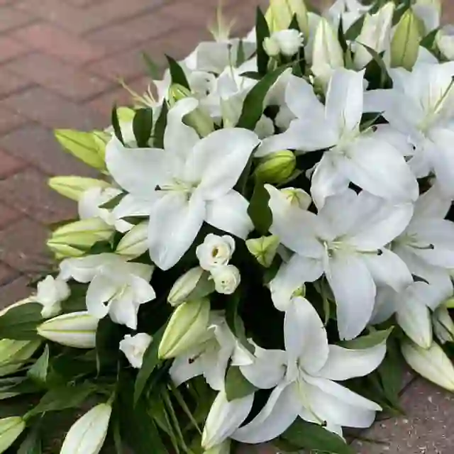 White lily sympathy casket spray by The Flower Shaq